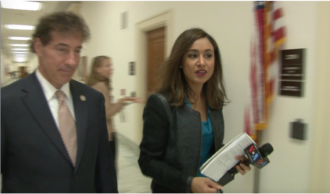 Reporter conducting a walking interview in a congressional hallway